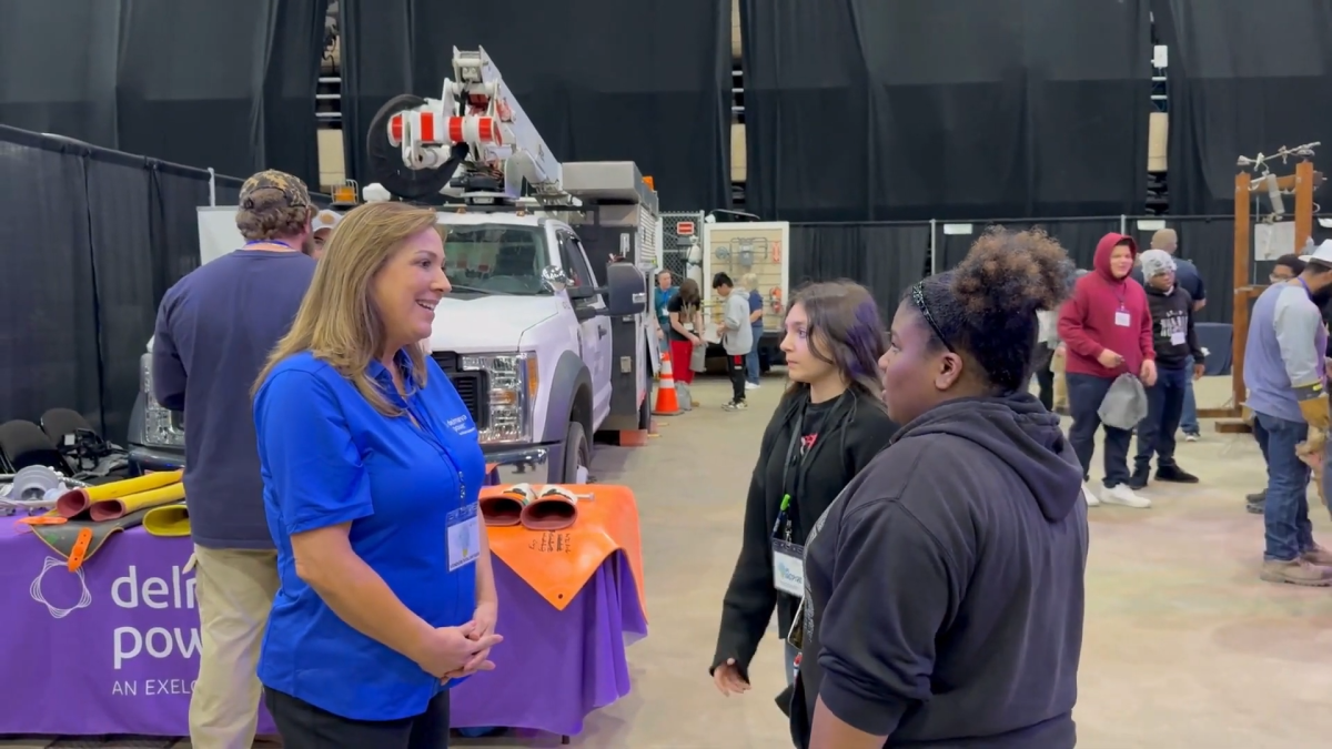 An adult talking to two young people at an event